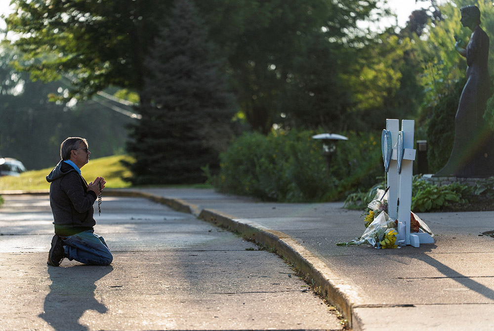 A man prays near crosses outside Annunciation Church in Minneapolis Aug. 28, 2025, following a shooting the previous day. A shooter opened fire with a rifle through the windows of the school's church and struck children attending Mass Aug. 27 during the first week of school, killing two and wounding 17 people in an act of violence the police chief called "absolutely incomprehensible." (OSV News/Reuters/Tim Evans)