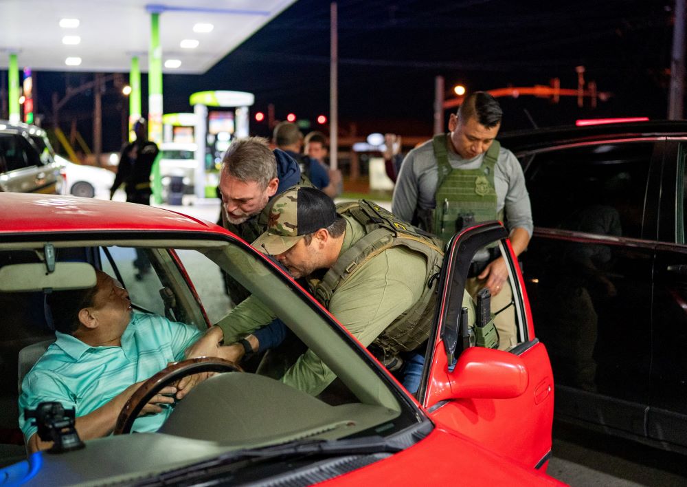 U.S. Immigration and Customs Enforcement officers detain a man from a car stopped by Tennessee Highway Patrol at a gas station in South Nashville, Tennessee.