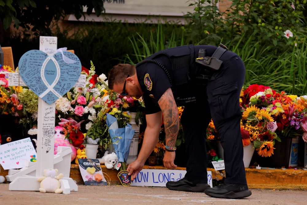 A police officer places a patch at a makeshift memorial at Annunciation Catholic Church. A police officer places a patch at a makeshift memorial at Annunciation Catholic Church.
