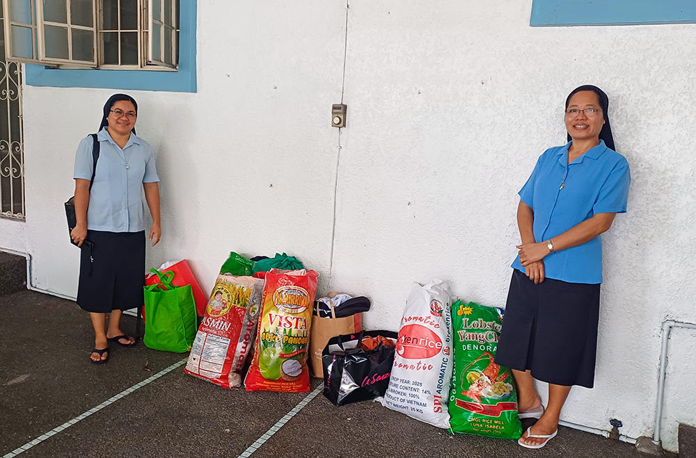 Sr. Flor Montojo Manga, left, and Sr. Linlee Vios flank sacks of donated clothes for the Aetas. (Oliver Samson)