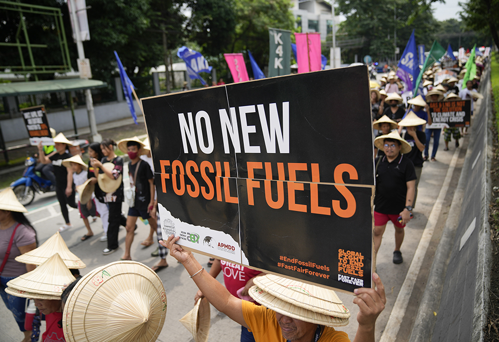 A protester holds a slogan as they join the global march to end fossil fuel on Sept. 15, 2023, in Quezon City, Philippines. (AP photo/Aaron Favila)