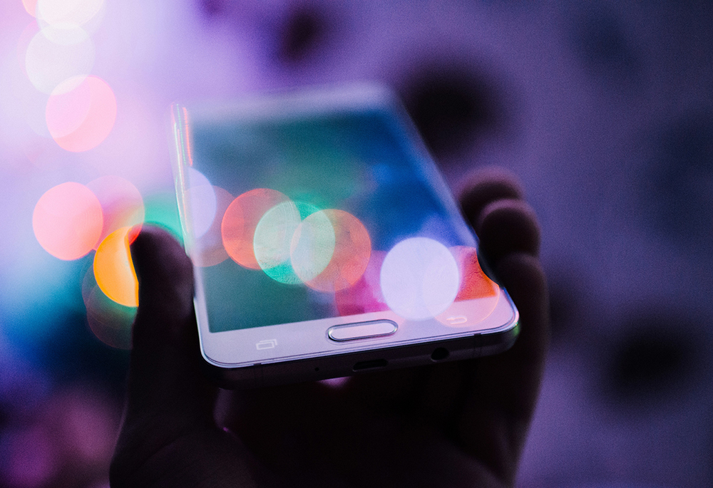 A person holds a smartphone in this photo illustration. (Unsplash/Rodion Kutsaiev)