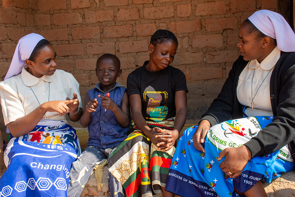Sr. Ruth Kuyumba, right, engages Memory Musonda and her son Joshua in a conversation during a home visit. Sr. Agnes Kateule, left, uses sign language to communicate with Joshua. Memory and Joshua were beneficiaries of the recently defunded Inclusive Family Strengthening project, formerly managed by the Sisters of Mercy with support from Catholic Relief Services. (Derrick Silimina)