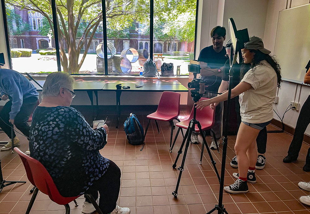 Students Duy Do, David Israel and Leila Jones set up for a podcast as Marianite of Holy Cross Sr. Judith Gomila waits to be interviewed at Loyola University New Orleans on July 23, 2024. (Claire Gallagher)