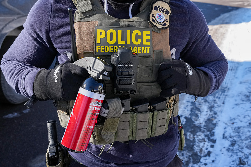 A federal agent holds a chemical canister while questioning a person Jan. 27, 2026, in Minneapolis. (AP/Adam Gray)