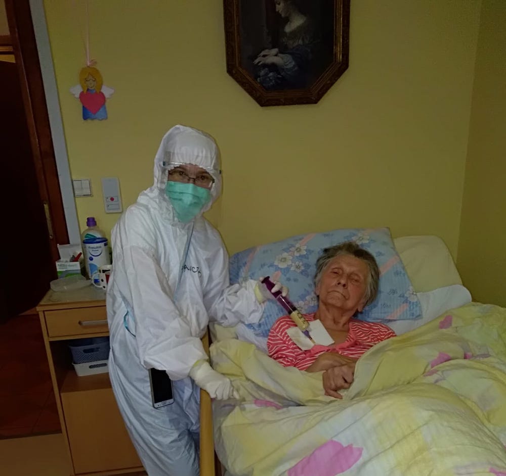 A Franciscan Sister of Love and Penance cares for a COVID-19 patient in Poland. Thousands of sisters in Poland have volunteered and worked in hospitals and health care centers during the pandemic, including 32 sister-doctors and 1,020 sister-nurses. A health care worker in personal protective equipment administers treatment to an elderly woman in bed because of COVID-19