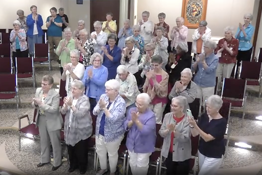 LCWR 2021 Elise Garcia ovation Sisters in the Adrian Dominican auditorium in Adrian, Michigan, give Dominican Sr. Elise García a standing ovation at the conclusion of her Aug. 11 presidential address to the Leadership Conference of Women Religious. (GSR screenshot)