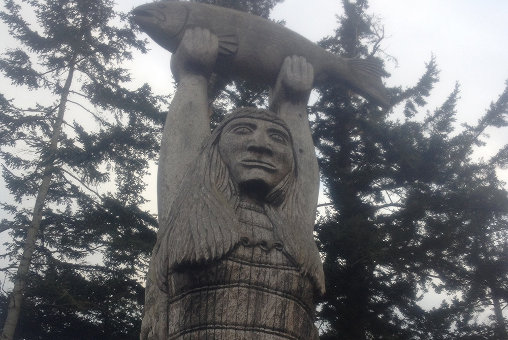 Magnuson Ted George carving A totem called "Ko-kual-alwoot" ("Maiden of the Sea"), carved by a Swinomish tribal member, stands near Deception Pass at Rosario Beach on the coast of Puget Sound, a few miles from the Suquamish Reservation. (Courtesy of The Cedar Tree Institute)