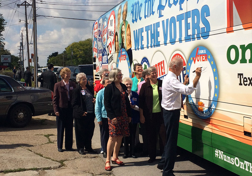 Vice President Joe Biden signs his name to the Network Nuns on the Bus official vehicle after speaking at the kickoff rally in front of the Iowa State Capitol in September 2014. Some of the Nuns on the Bus, including Sr. Simone Campbell, in red shoes, sta Vice President Joe Biden signs his name to the Network Nuns on the Bus official vehicle after speaking at the kickoff rally in front of the Iowa State Capitol in September 2014. Some of the Nuns on the Bus, including Sr. Simone Campbell, in red shoes, sta