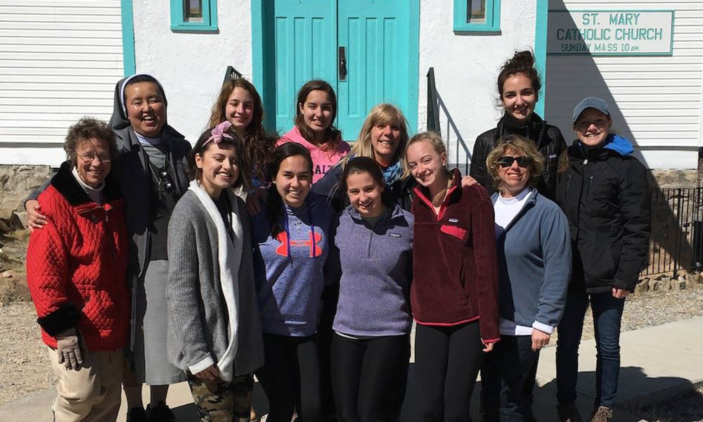 Sr. Patricia Bietsch, left (in red jacket) stands in front of St. Mary Mission church with students from Lauralton Hall, Our Lady of Mercy High School, in Milford, Connecticut, during their immersion trip in March 2017. (Provided photo) Sr. Patricia Bietsch, left (in red jacket) stands in front of St. Mary Mission church with students from Lauralton Hall, Our Lady of Mercy High School, in Milford, Connecticut, during their immersion trip in March 2017. (Provided photo)