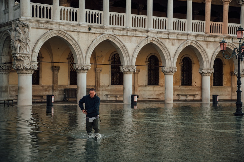 A man wades through knee-high flood waters in St. Mark's Square, Venice, Italy. (Unsplash/Egor Gordeev) A man wades through knee-high flood waters in St. Mark's Square, Venice, Italy. (Unsplash/Egor Gordeev)