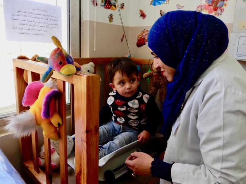 A nurse at the Pontifical Mission Mother of Mercy Clinic in Zarqa weighs a young Syrian refugee ahead of his vaccinations. A nurse at the Pontifical Mission Mother of Mercy Clinic in Zarqa weighs a young Syrian refugee ahead of his vaccinations.