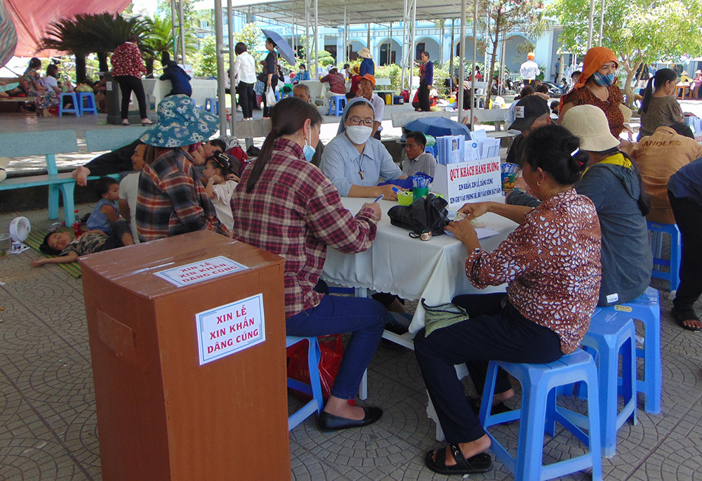 Pilgrims make donations and give their intentions of prayers to a nun. (Joachim Pham) Pilgrims make donations and give their intentions of prayers to a nun. (Joachim Pham)