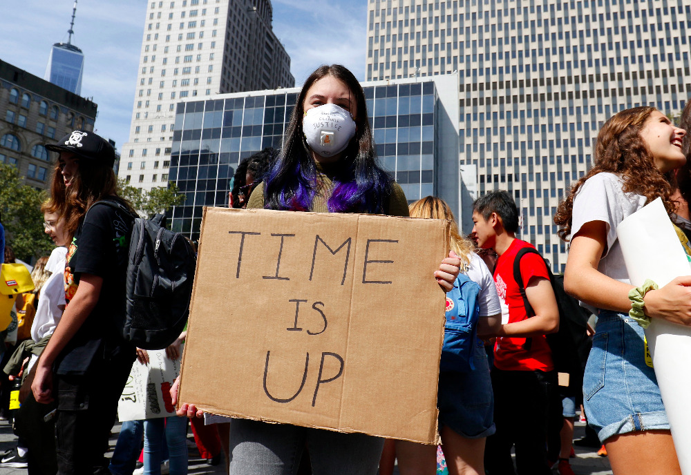 A young woman wears an air-filtering mask and holds a sign while participating in the Global Climate Strike in New York City in September 2019. (CNS photo/Gregory A. Shemitz)