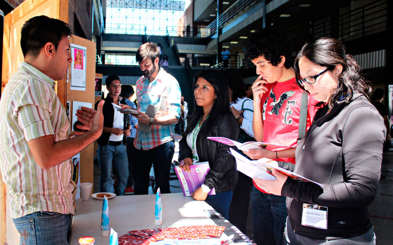 Nelson Pineda, a volunteer from Aspidh Arcoiris Trans de El Salvador, speaks with conference attendees in front of a memorial to trans women who have been murdered in El Salvador in the past decade. Aspidh Arcoiris is a Salvadoran non-profit organization that works primarily with transgender, transsexual and transvestite individuals in the areas of human rights and HIV prevention. (Courtesy of ALDES El Salvador)