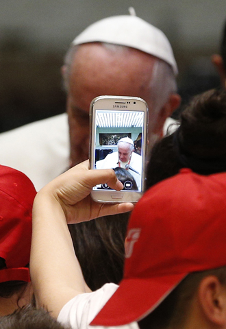 A youth takes a photo on a cell phone as Pope Francis meets children of Italian prisoners in Paul VI hall at the Vatican May 30. (CNS photo/Paul Haring)