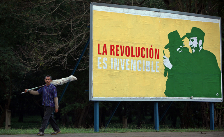 In this Dec. 26, 2014, file photo, a man walks past a Cuban revolutionary banner in Havana. (CNS/Alejandro Ernesto, EPA)
