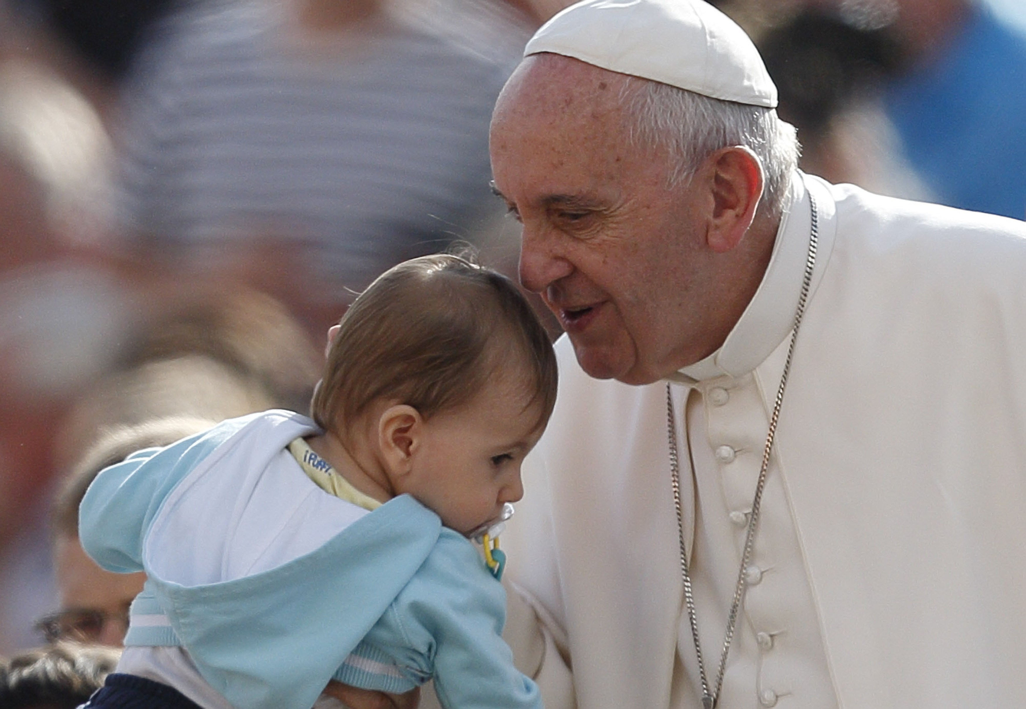 Pope Francis greets a baby during his general audience in St. Peter's Square at the Vatican Oct. 7. The pope said that when families mirror God's love for all, they teach the church how it should relate to all people. (CNS/Paul Haring)