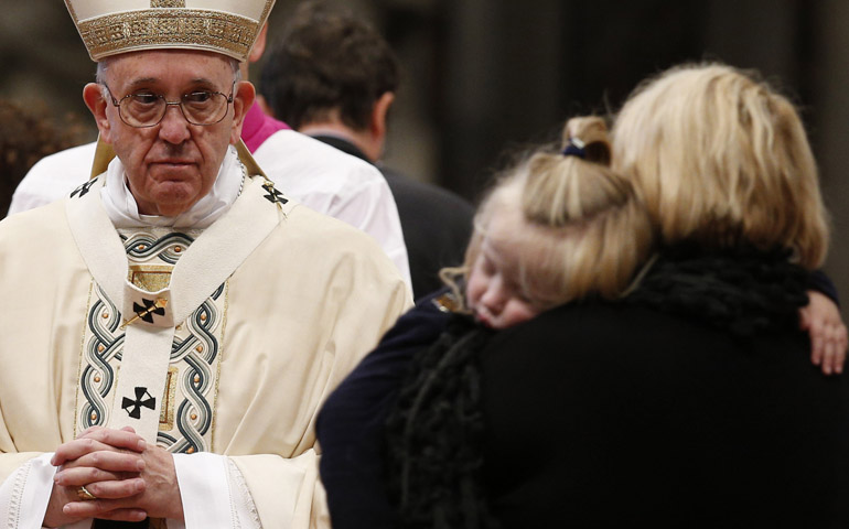 Pope Francis accepts offertory gifts from a mother holding her sleeping child during a Mass marking the feast of the Epiphany at the Vatican Jan. 6. (CNS/Paul Haring)
