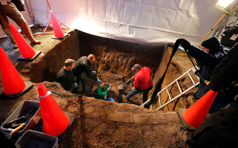 Medical examiner Nathaniel Patterson, forensic anthropologist Mark Johnsey and archaeologist Deacon David Keene remove soil from the grave of Fr. Augustus Tolton Dec. 10 as his remains are exhumed and verified at St. Peter Cemetery in Quincy, Ill. (CNS / Karen Callaway, Catholic New World)