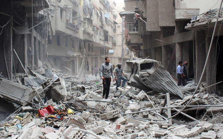 Civilians inspect a damaged site May 14 after what activists said were airstrikes by forces loyal to Syria's President Bashar al-Assad in the Damascus suburb of Ain Tarma. (CNS/Reuters)