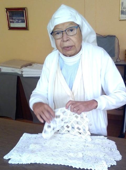 SISTER JOAQUÍNA HERNÁNDEZ PEREIRA, midwife. The sister stands at a table, handling textiles.