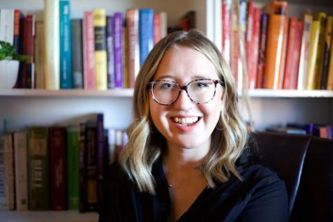 Anneli Loepp Thiessen, doctoral candidate at the University of Ottawa. Thiessen smiles from desk chair, in background is bookshelf.