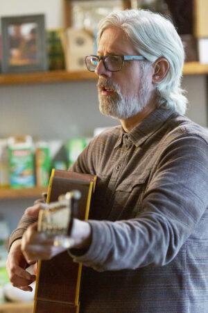 Matt Maher, Catholic songwriter. Maher stands strumming guitar.