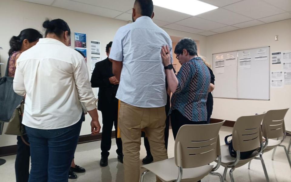 Sr. Leticia Gutiérrez Valderrama, right, and others from a migrant ministry group, prays with a man in a room at an immigration court in El Paso June 25. Gutiérrez, a Scalabrinian sister, has been leading the diocese's efforts in El Paso's immigration court, comforting and helping women, children and men facing detention and deportation. (Courtesy of Hope Border Institute) 
