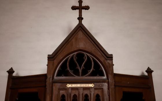 A brown confessional with a cross on the top