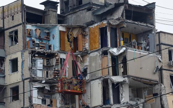 Emergency personnel are seen Jan. 16 working at the site where an apartment block was heavily damaged by a Russian airstrike in Dnipro, Ukraine. At least 30 people were killed in the airstrike, the national emergencies service reported as rescue workers scrambled to reach survivors in the rubble. (OSV News photo/Reuters/Clodagh Kilcoyne)