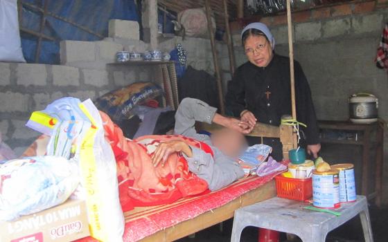 Filles de Marie Immaculée Sr. Lucia Nguyen Thi Ngo offers rice, instant noodles and milk to a patient (whose face is obscured to protect identity) Nov. 12, 2022, in Vietnam's Phu Loc district. (GSR photo/Joachim Pham)