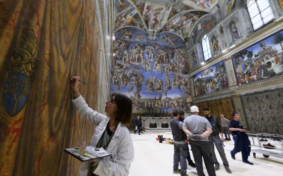 As a restorer with the Vatican Museums touches up a wall fresco in the Sistine Chapel at the Vatican May 2, 2025, workers prepare to build platforms over a protective covering on the marble floor May 2, 2025. The cardinals who enter the conclave to elect a new pope May 7 will sit at tables facing the center of the chapel with the tables in the back row raised slightly. (CNS photo/Vatican Media)