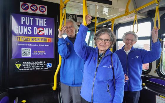 From left: Bon Secours Srs. Pat Dowling, Elaine Davia and Nancy Glynn stand beside an ad reading, "Put the Guns Down. Let Peace Begin with Us," inside a Baltimore city bus. The ad campaign runs through June on the outside and inside of city buses, and on Baltimore's subway. (Courtesy of Sisters of Bon Secours)