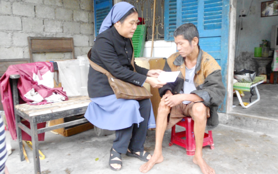 Daughters of Our Lady of the Visitation Sr. Mary Pham Thi Phu offers gifts to a man in Phu Loc District in Thua Thien Hue Province on April 19. Their community's ministry includes supporting people affected by Agent Orange and landmines left behind after the Vietnam War. (GSR photo)
