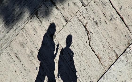 Shadows of two people walking along a street (Unsplash/Anne Nygard)