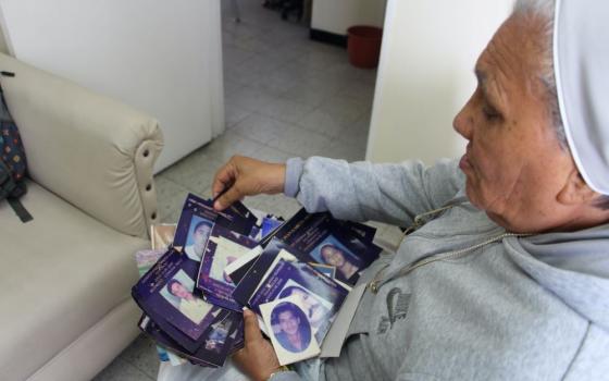 Sr. Rosa Cadavid looks at photos of victims of violence at the Madre Laura Montoya Foundation. Foundation volunteers are in the process of reorganizing the gallery that once held the photos of people mourned as victims of violence in Medellin, Colombia. (Tracy L. Barnett)
