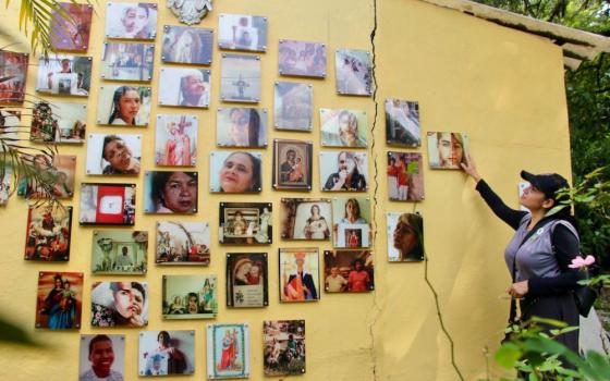 Carmen Jiménez explains to visitors the Comuna 13 cemetery's wall of portraits honoring victims and their mothers. Among them are haunting composite images: half the face is that of a missing son or daughter, the other half their grieving mother — their features fused into a single, powerful symbol of loss and remembrance. (Tracy L. Barnett)