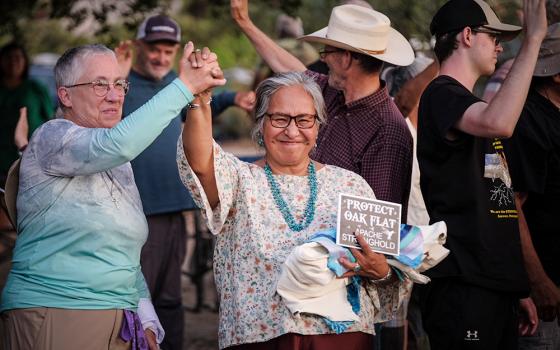 Diné elder and adviser to the delegation, Pat McCabe, center, and Providence Sr. Barbara Battista grab hands in celebration and solidarity at the gathering, held July 18-20, in defense of Oak Flat in southeastern Arizona's Tonto National Forest. (Courtesy of Steve Pavey)