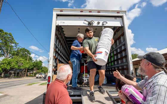 Ethan Clark, a parishioner and volunteer with the Notre Dame Parish relief distribution center in Kerrville, Texas, unloads buckets from a truck of donations that will be used to store the items for emergency cleanup kits. (GSR photo/Gregg Brekke)