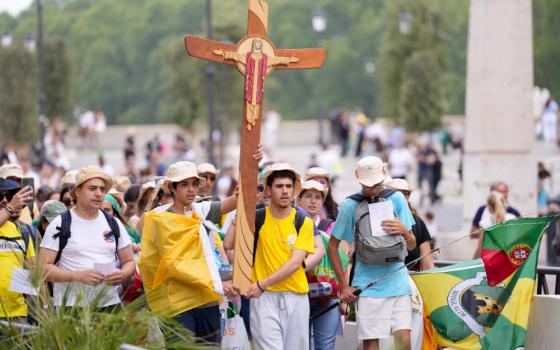 Young pilgrims carry a cross as they walk toward the Vatican during a pilgrimage in Rome, July 28, 2025. (CNS/Lola Gomez)