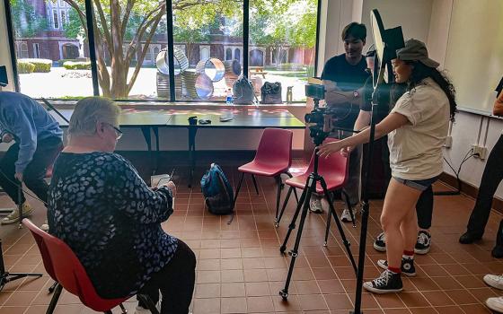 Students Duy Do, David Israel and Leila Jones set up for a podcast as Marianite of Holy Cross Sr. Judith Gomila waits to be interviewed at Loyola University New Orleans on July 23, 2024. (Claire Gallagher)
