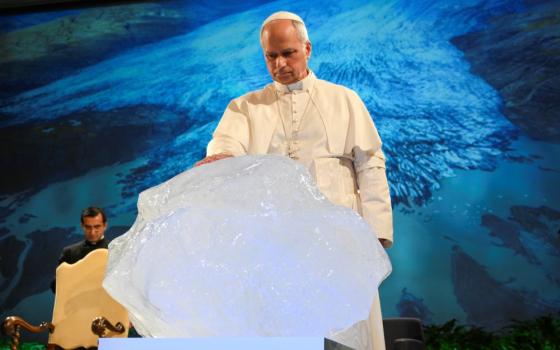 Pope Leo XIV blesses a chunk of ice from a glacier in Greenland during the opening session of an international conference celebrating the 10th anniversary of Pope Francis' encyclical "Laudato Si', on Care for Our Common Home," at the Mariapolis Center in Castel Gandolfo, Italy, Oct. 1. The ice block was fished out of the Nuup Kangerlua fjord in Greenland after becoming detached from the ice sheet. (CNS/Vatican Media)