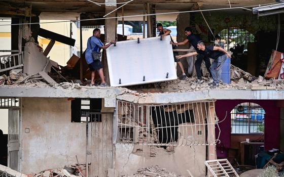 People carry personal belongings at a damaged building in Catia La Mar, Venezuela, Jan. 4, 2026, following U.S. strikes the previous day on Venezuela during which President Nicolas Maduro and his wife, Cilia Flores, were captured. (OSV News/Reuters/Gaby Oraa)
