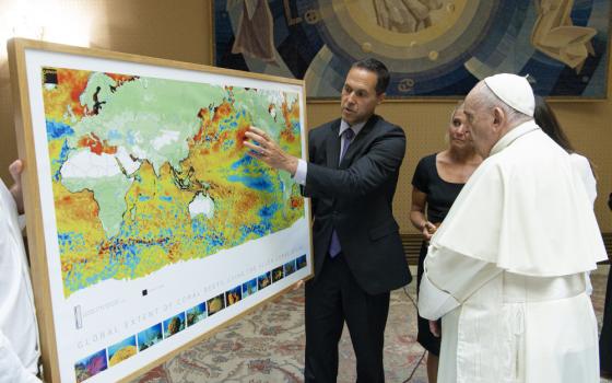Ecologist Gregory Asner of Arizona State University shows Pope Francis a map from a new atlas of the world's coral reefs in August at the Vatican. (Courtesy of Vatican Media)